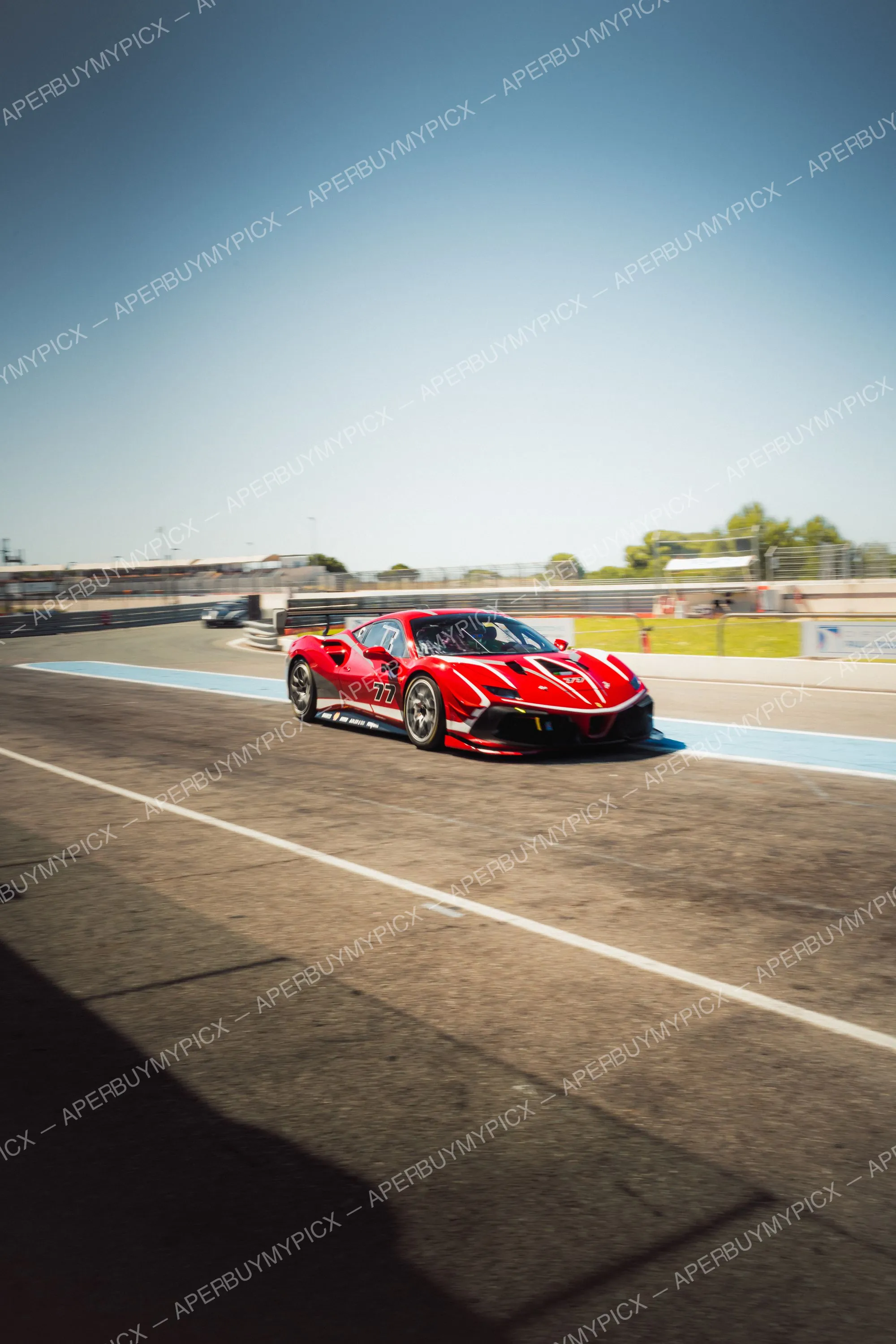 Ferrari 488 Challenge rouge numéro 77 roulant sur le circuit du Castellet avec bordures bleues et ciel dégagé, effet de vitesse en filé