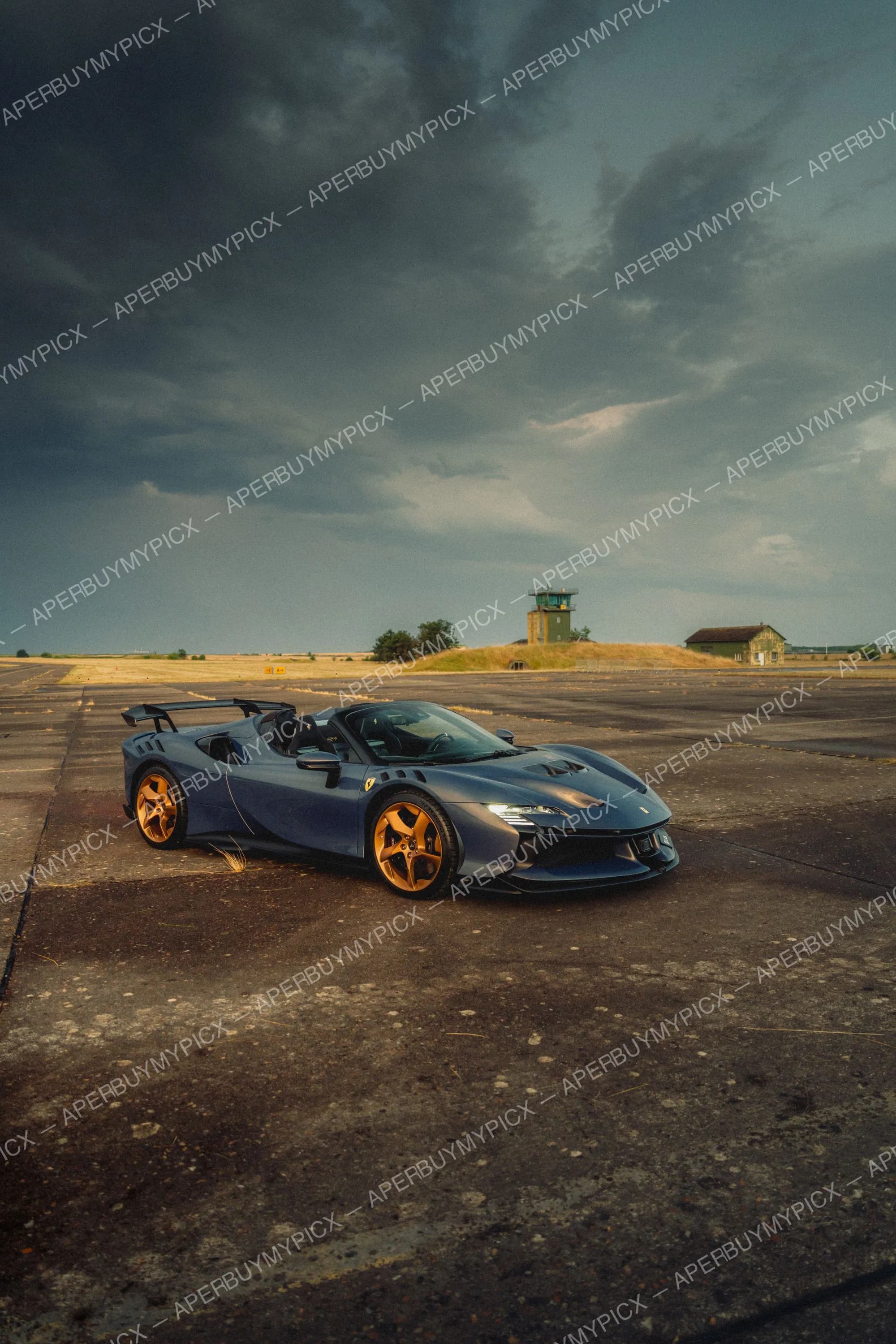 Supercar Ferrari SF90 bleu foncé avec jantes dorées garée sur une ancienne piste d'aéroport, sous un ciel orageux avec tour de contrôle en arrière-plan