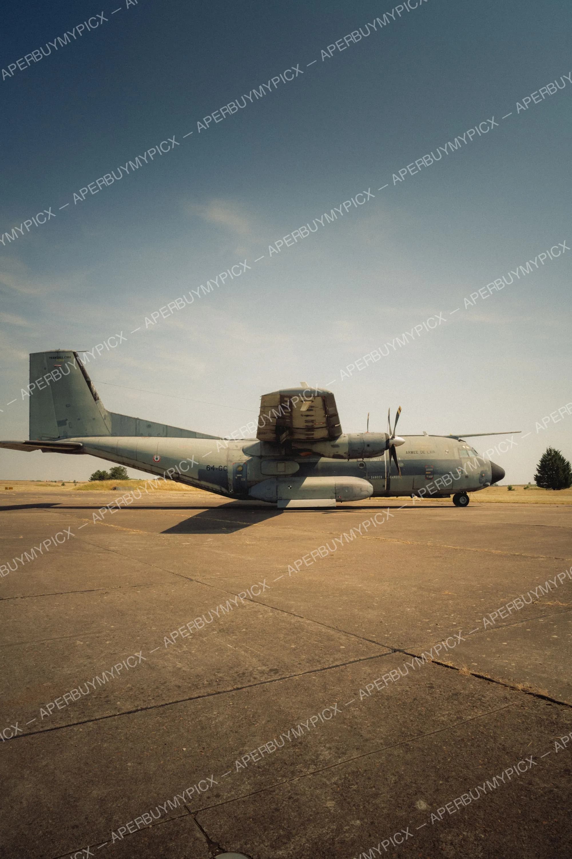 Avion de transport militaire Transall C160 de l'Armée de l'Air stationné sur le tarmac sous un ciel bleu, vue latérale avec hélices et empennage en T.
