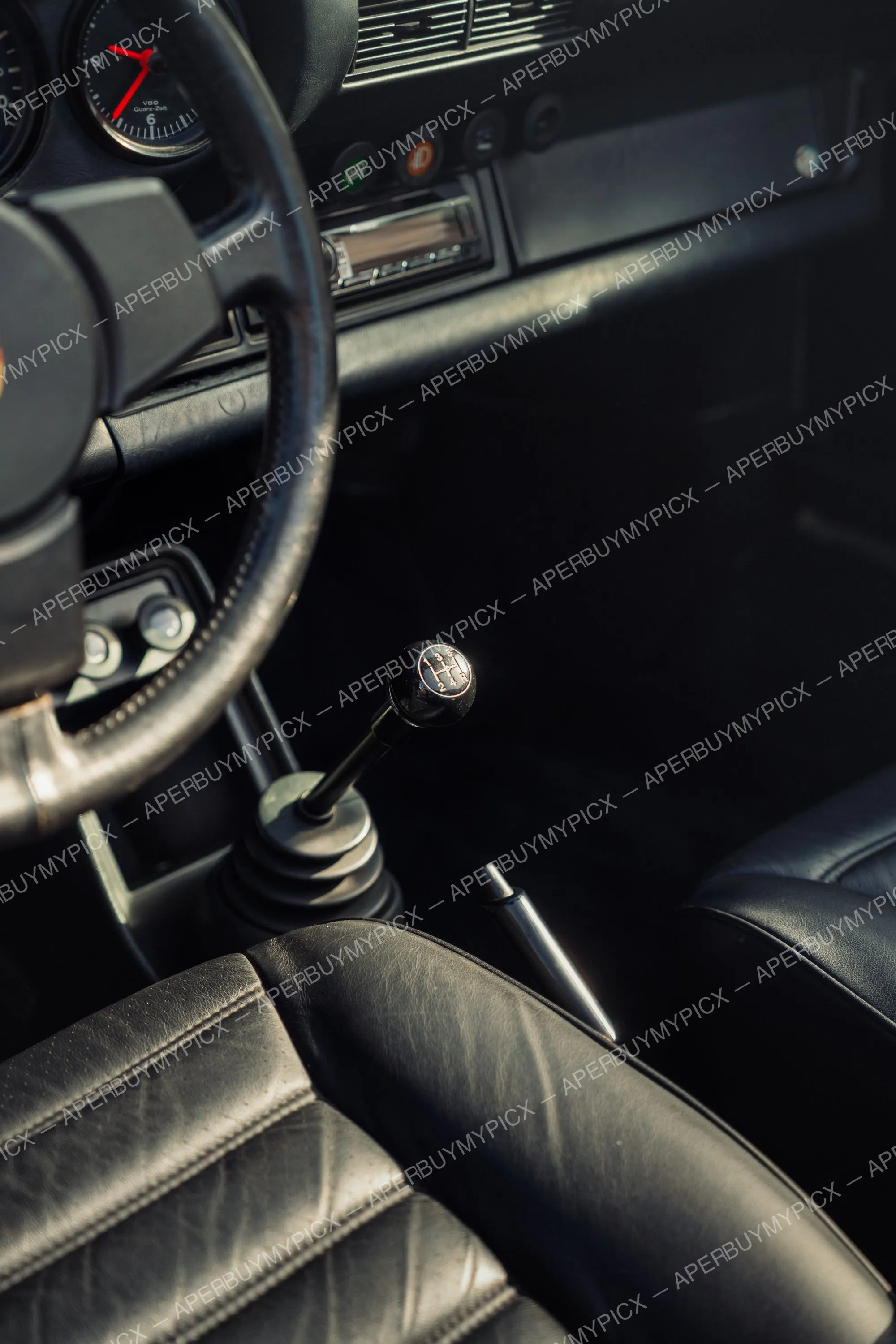 Intérieur cuir noir d'une Porsche 911 SC Targa avec levier de vitesses 5 rapports, volant, compteur VDO Quarz-Zeit et frein à main chromé