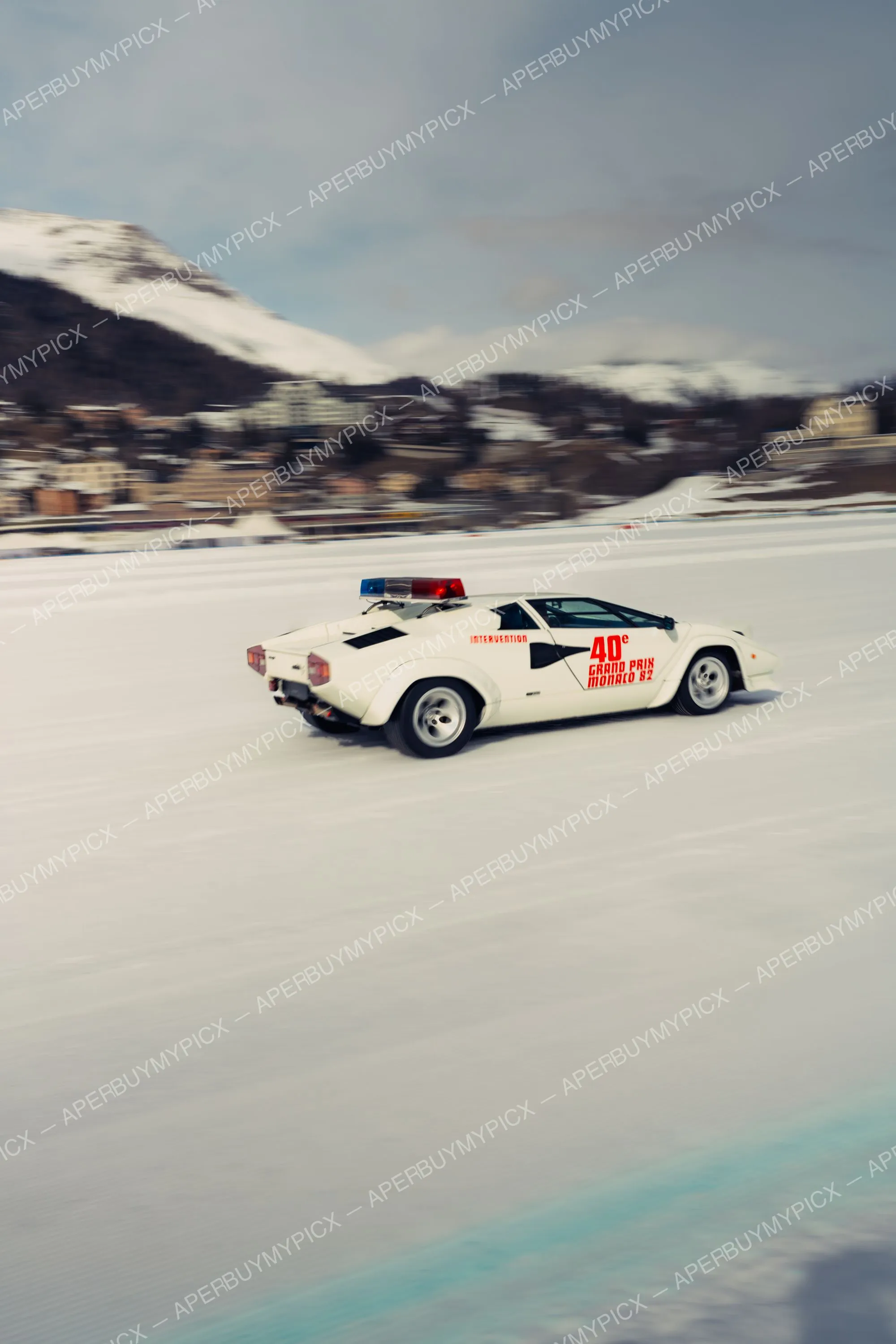 Lamborghini Countach blanche avec gyrophares roulant à vive allure sur un lac gelé à St. Moritz, montagnes enneigées en arrière-plan