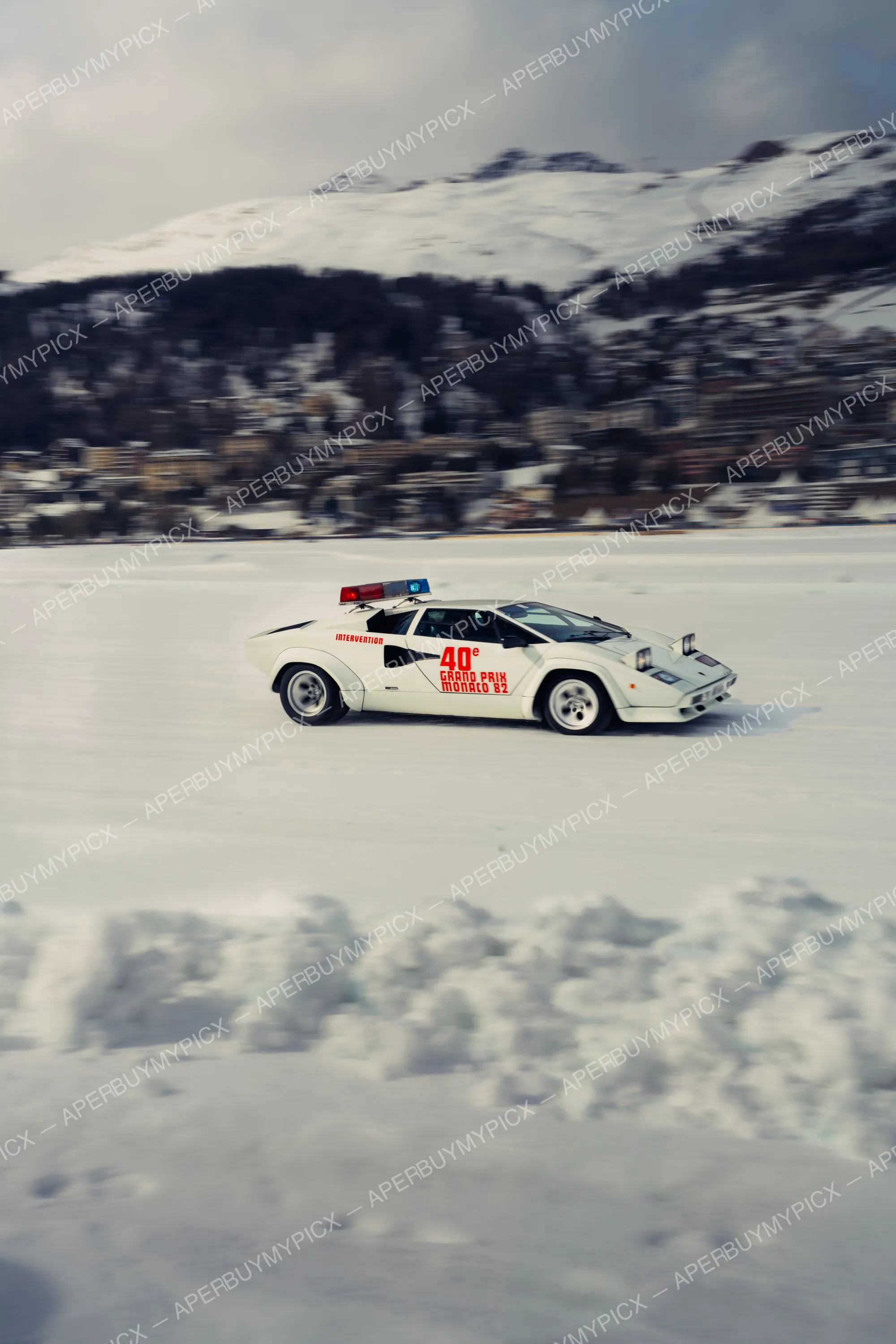 Lamborghini Countach blanche marquée Intervention 40e Grand Prix Monaco 82 avec gyrophares, en mouvement sur un lac gelé enneigé devant une montagne à St. Moritz